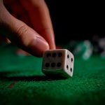Croupier hand rolling the dice on green poker table