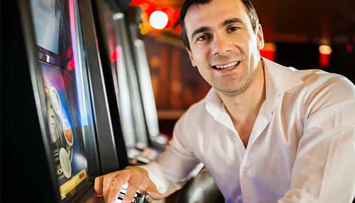 A man in white shirt playing a slot machine