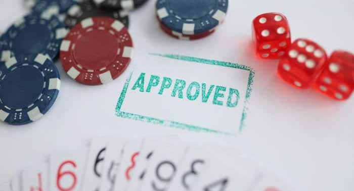 Stamp approved standing near playing cards and chips in casino with dice